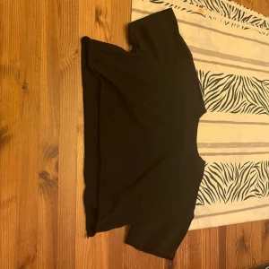 Svart croppad topp från Bik Bok - En svart croppad topp från Bik Bok i storlek L. T-shirten har korta ärmar och rund halsringning. Enkel och stilren design i mjukt bomullsmaterial, perfekt att matcha med höga jeans eller kjol.