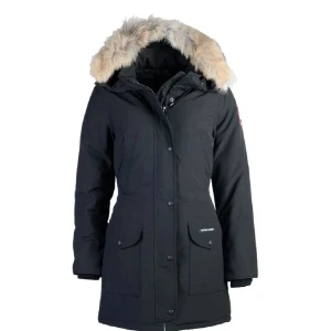Svart parkas från Canada Goose med päls - Säljer en Canada goose trillum parka med stor huva och beige päls. Jackan har klassisk logga på ärmen, stora fickor framtill och stängs med både dragkedja och knappar. Perfekt för kalla dagar och riktigt snygg till vintern. Säljer denna för den har inte kommit till användning sedan jag köpte den.