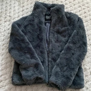Mörkgrå pälsjacka från River Island - Säljer en fluffig och mysig mörkgrå pälsjacka från River Island i storlek xs. Jackan är väldigt bra skick. Den är perfekt för dig som vill ha en cool och varm look under kyliga dagar.
