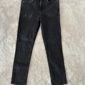 Svarta jeans från NN07, storlek 29/32 - Säljer ett par klassiska svarta jeans från NN07 (No Nationality) i storlek 29/32. Jeansen är i mycket fint skick och endast använda ett fåtal gånger, utan slitningar eller skador. Modellen har en smal passform som sitter snyggt men är ändå bekväma.