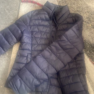 Svart pufferjacka från ONLY XS - Säljer en svart pufferjacka från ONLY i storlek XS. Jackan har quiltad design, hög krage och dragkedja framtill. Perfekt för kyliga dagar och har en clean, stilren look som funkar till det mesta.