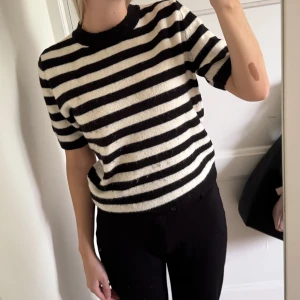 Randig stickad tröja från H&M - Snygg stickad tröja från H&M med breda svarta och vita ränder. Tyvärr lite nopprig nertill därav billig. 