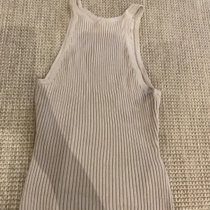 Beige ribbad linnetopp från H&M - Säljer en beige ribbad linnetopp från H&M i storlek S. Toppen har en tight passform med breda axelband och ärmlös design. Perfekt att styla med jeans eller kjol för en clean look. Materialet är mjukt och stretchigt för extra komfort.