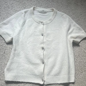 Vit kortärmad kofta från H&M - Kortärmad stickad T-shirt med silverfärgade knappar! Bra skick, storlek XS💖