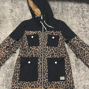 Leopardmönstrad skidjacka CLWR S - Snygg skidjacka från CLWR i storlek S med leopardmönster. Jackan har fyra stora fickor med lock, huva med snörning och hel dragkedja framtill. 