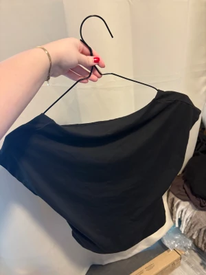 Svart offshoulder topp i bomull - Säljer en svart topp med öppenrygg . Toppen har en snygg, bred halsringning som ger en cool och avslappnad vibe. Materialet känns mjukt och skönt, troligen bomull. Perfekt att styla med jeans eller kjol för en trendig look.