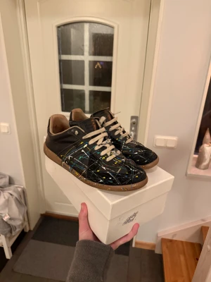 Maison Margiela 43 - Tja säljer nu mina Maison Margiela i storlek 43 med ett unikt färgstänk på, box samt dustbag finns dock inget kvitto! 🧾Inga defekter finns, hör av dig vid fråga eller prisförslag!😄