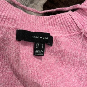 Rosa stickad tröja från Vero Moda - Mysig rosa stickad tröja från Vero Moda i storlek S. Tröjan har rund halsringning, långa ärmar och ribbade muddar vid hals, ärmslut och nederkant. Perfekt för dig som gillar en enkel och chill stil med lite färg.
