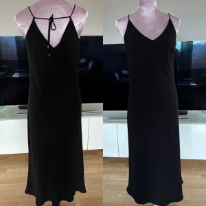 Klänning med snörning i ryggen - Storlek M från Lindex. Justerbart band/snörning i ryggen och har underkjol. Lapp med skötselråd bortklippt. Mycket fint skick inte mycket använd. Har inga defekter men metallbitarna på snörena lite missfärgade som man ser på bild.  Längd ca 117 cm Från armhåla till armhåla ca 50 cm