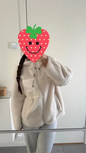 Vit teddyjacka med huva från H&M - Mysig vit teddyjacka från H&M med huva och snörning. Jackan har en cool bröstficka med dragkedja och två sidofickor. Perfekt för kalla dagar, med oversized passform och fluffigt fleece-material. Använt några gånger, som ny