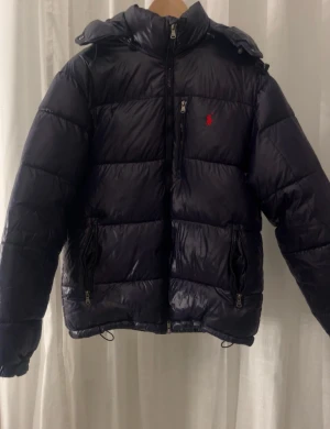 Populär dunjacka från Polo Ralph Lauren - Säljer min brors jacka som är väldigt populär och snygg, passar till allt. Väldigt bra skick nästan oanvänd då han redan tröttnat på den. Den är äkta såklart vilket man kan skanna och se på qr koden. Den är en xs men passar s-m tycker jag. Pris kan diskuteras vid snabb affär. 