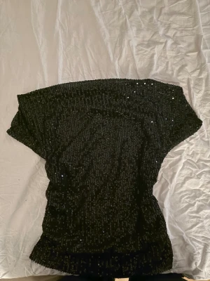 Svart paljett topp Gina Tricot - Säljer en svart topp från Gina Tricot, täckt med glittriga paljetter. Toppen är i strlk 158/164 och använd vid 1 tillfälle. Perfekt till nyår och fest. ✨🪩