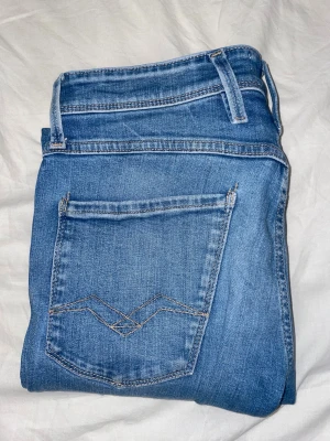 Replay Anbass Slim Fit jeans blå - Snygga ljusblå Replay Anbass jeans med slim fit och klassisk femficksdesign. Jeansen har snygga detaljer som kontrastsömmar och Replay-logga vid fickan. Tillverkade i mjukt jeansmaterial med stretch för skön passform.