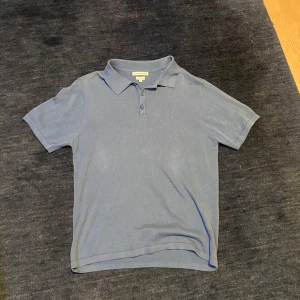 Blå pikétröja - Snygg blå pikétröja med klassisk krage och två knappar framtill. Tröjan är kortärmad och har en stilren look som passar perfekt till jeans eller shorts. Tillverkad i mjuk bomull för en skön känsla hela dagen.