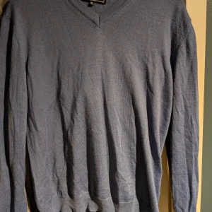 Blå stickad v-ringad tröja XL - En klassisk italiensk blå stickad tröja med v-ringning och långa ärmar. Enkel och stilren design som passar till många olika outfits.