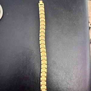 Guldigt armband med Lacoste logga - Snyggt Lacoste armband i guldton med rektangulära länkar och graverade mönster. Låset har den klassiska Playboy-kaninen ingraverad. Perfekt för dig som gillar statement-smycken med lite edge och exklusiv känsla.