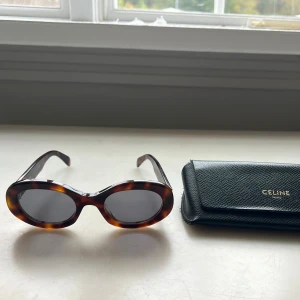 Celine Triomphe solglasögon brun - Snygga och populära solglasögon från Celine Paris i brunmelerad sköldpaddsmönstrad plast med mörka glas. Guldiga Celine-loggor på sidorna och medföljande svart fodral. Har bytt glaset till ett mer reptåligt glas då jag repade ner förra glaset ❣️ Nypris 4950 kr ❣️