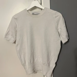 Vit t-shirt från Zara  - Enkel och stilren vit t-shirt från Zara. T-shirten har rund halsringning och korta ärmar med ribbade muddar. 