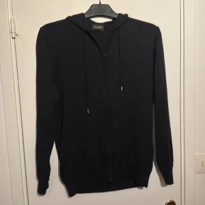 Svart hoodie från Sand Copenhagen - Svart hoodie från Sand Copenhagen med dragkedja framtill och snörning i huvan. Storlek M/S