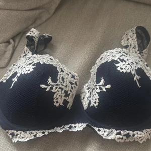 Intimissimi bh - Supersnygg mörkblå  bh med vit blommig spetsbrodyr längs kuporna och axelbanden. Oanvänd.