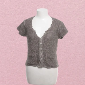 Kortärmad stickad blus  - Kortärmad stickad kofta/topp med söta detaljer vid kragen, knappar och små fickor. Liten i storlek enligt min uppfattning  V ringad  Inga defekter! Från märket Simclan