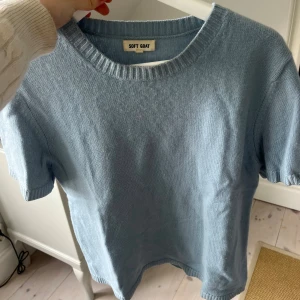 Ljusblå stickad t-shirt från Soft Goat - Supermjuk ljusblå stickad t-shirt från Soft Goat med rund halsringning och ribbade kanter. Perfekt för dig som gillar en clean och chill look. T-shirten har korta ärmar och är gjord i ett lyxigt material som känns riktigt skönt mot huden.