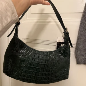 Krokodilskinn handväska grön - Fin handväska i äkta krokodilskinn. Oanvänd med lapp på. Köptes för 2000kr. Fin grön färg