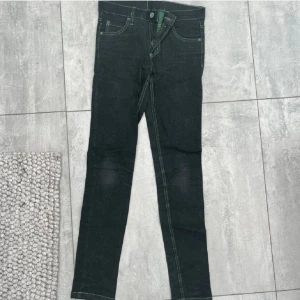 Svarta Cheap Monday skinny jeans - Säljer ett par svarta skinny jeans från Cheap Monday med klassisk logga bak på linningen. Jeansen har kontrasterande sömmar och femficksmodell. Perfekta för dig som gillar en tight passform och stilren look.