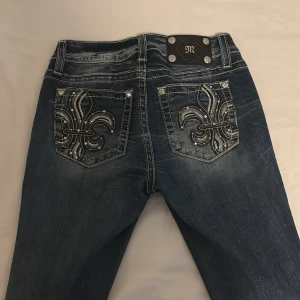 Miss Me jeans med broderade bakfickor - Snygga blå jeans från Miss Me med broderade och glittriga detaljer på bakfickorna. Jeansen har tydliga kontrastsömmar, silverfärgade knappar med stenar och klassisk femficksmodell. Materialet är jeans med stretch och är bootcut. För mer info som t.ex midje mått kontakta privat💕