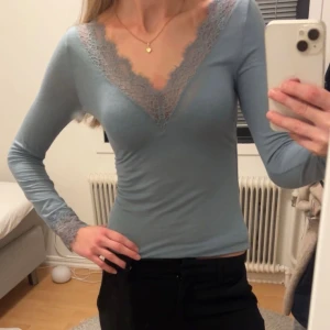 Intimissimi spetstopp - Säljer en ljusblå långärmad topp med v-ringning och fina spetsdetaljer längs halsringningen och vid ärmsluten. Toppen har en slim passform och är perfekt för dig som gillar en feminin och stilren look. Använd 2 gånger så nyskick!!