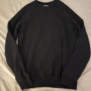 Svart sweatshirt från Pier One - En stilren svart sweatshirt från Pier One med rund hals och ribbade muddar vid ärmslut och nederkant. Tröjan har en klassisk passform och är tillverkad i mjuk bomull, perfekt för chill dagar eller när du vill ha en enkel look.