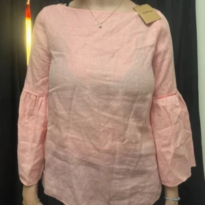 Ljusrosa blus i linne med vida ärmar - Superfin ljusrosa blus . Blusen har vida, trekvartsärmar med lätt volang och en rak, avslappnad passform. Perfekt för dig som gillar en enkel men ändå trendig look.