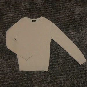 Beige ulltröja från Massimo Dutti - Säljer en stilren beige stickad tröja från Massimo Dutti i extrafin ull. Tröjan har rund halsringning, ribbade muddar och lång ärm. Perfekt för lager-på-lager under kyliga dagar.