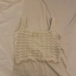 Vit stickad linnetopp med spetsmönster - Superfin vit stickad linnetopp med breda axelband och ett detaljerat spetsmönster. Toppen är croppad och har en vågig kant nertill som ger en söt touch. Perfekt för semester och varma sommar dagar på stranden. Pris kan diskuteras 