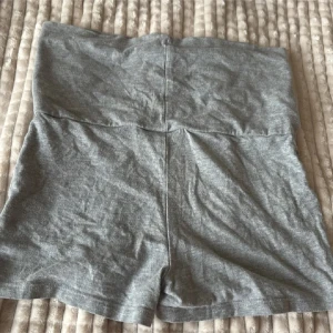 Grå höga shorts i mjuk bomull - Säljer ett par gråa shorts med hög midja, tillverkade i mjukt och stretchigt bomullstyg. De har en enkel och clean design utan synliga detaljer eller mönster, perfekt för chill dagar eller när du vill ha något bekvämt. Passformen är loose och de är riktigt sköna att ha på sig.