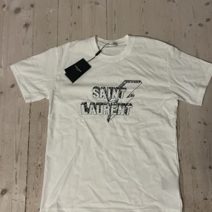 Saint Laurent T-shirt - Helt ny Fet tisha ifrån saint Laurent i S. Tröjan är aldrig använd och är i topp skick. Skriv om du har några frågor. vet ej om varan är äkta då jag har köpt den i andrahand