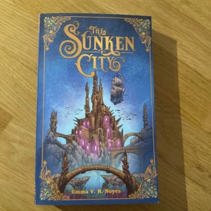 The Sunken City - Följ med på ett episkt äventyr till en magisk stad under ytan! Med ett färgstarkt omslag och fantasifulla illustrationer lockar denna bok unga läsare som älskar mystik, äventyr och fantastiska världar.