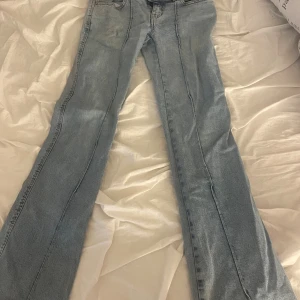 Ljusblå bootcut jeans från 157 - Säljer ett par ljusblå jeans från 157 i storlek S. Jeansen har bootcut-modell med full längd och klassisk femficksdesign. De är tillverkade i denim och har markerade sömmar längs benen för en snygg detalj. Perfekta för dig som gillar retrovibbar och bekväm passform.