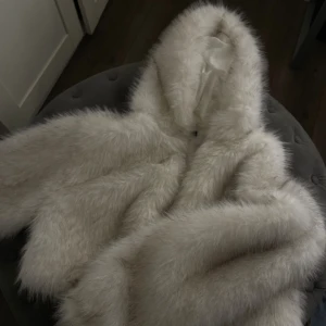 Vit fluffig pälsjacka med huva - Använd en gång pälsjacka med luva.