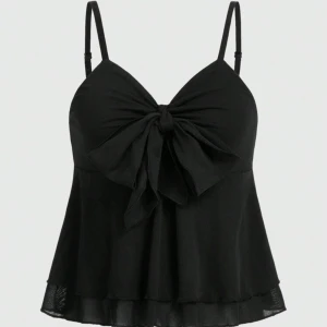 Svart linnetopp med rosett - Snygg svart linnetopp med tunna justerbara axelband och stor rosett framtill. Toppen har en lätt utsvängd form med volangkant i mesh nedtill som ger en extra touch. Perfekt för dig som gillar detaljer och vill ha en feminin look.