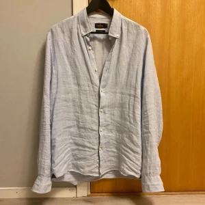 Ljusblå - linneskjorta från Morris - Snygg ljusblå skjorta från Morris i 100% linne. Button down-krage och lång ärm. Perfekt för dig som gillar en stilren och luftig look.                                                         Storlek: M (passar S)                                                                              Skick: 10/10                                                                          Nytt pris: Ca 1299kr                                                            ❗️Kontakta mig vid minsta lilla fråga❗️