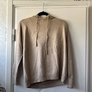 Beige stickad hoodie med huva - Beige stickad hoodie med huva och dragsnören.  Helt ny är tröjan/ aldrig använd för att den är för liten och då tänkte att jag säljer den vidare