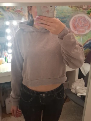 Ljuslila cropped hoodie med tryck - Säljer en ljuslila cropped hoodie med huva och ribbade muddar. På ryggen finns ett stort tryck med hjärta, eld och texten 'Love Hurts' och 'My soul is burning'. Hoodien har en avslappnad passform och är perfekt för en chill look. Materialet känns mjukt men ganska tunnt. Säljer för att jag inte gillar trycket så den är inte mycket använd