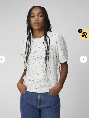 Vit spetsblus med puffärm - Superfin vit blus med korta puffärmar och vackert broderat spetsmönster. Blusen har rund halsringning och är tillverkad i ett lätt och luftigt material som passar perfekt till jeans eller kjol. Från ”object” i storlek S!