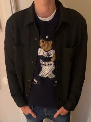 Svart overshirt med knappar - Stilren svart overshirt med klassisk krage och knäppning framtill. Två bröstfickor och raka ärmar ger en clean look. Perfekt att bära över en t-shirt eller tröja för en avslappnad men snygg stil.