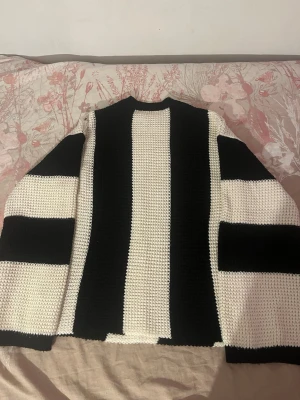 Svartvit randig stickad tröja - Säljer en stickad tröja med breda svarta och vita ränder. Tröjan har rak passform, rund halsringning och långa ärmar med samma randiga mönster. Materialet är grovstickat och ger en cool, avslappnad vibe. Perfekt för dig som gillar grafiska mönster.