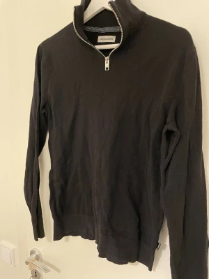 Svart halvzip-tröja Jack & Jones - Svart långärmad tröja från Jack & Jones med halv dragkedja och hög krage. 