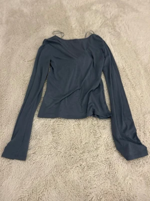 Blå omlottopp med knytband - Trendig blå omlottopp med långa ärmar och snygga knytband framtill. Tunn och mjuk kvalitet som ger en skön känsla. Jag har inte använt så mycket och den har nästan inga tydliga märken på användning.