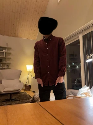 Vinröd skjorta från Ralph Lauren - Säljer en vinröd skjorta från Ralph Lauren med klassisk krage och knappar framtill. Skjortan har lång ärm och den ikoniska gröna loggan broderad på bröstet. Perfekt till jeans eller chinos för en clean och stilren look.