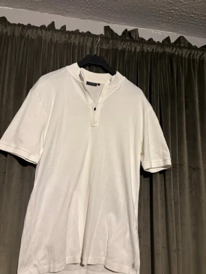 Vit kortärmad polotopp med dragkedja - Vit kortärmad polotopp från J.lindeberg med liten ståkrage och dragkedja framtill. Tillverkad i mjuk bomull, perfekt för en clean och stilren look. Enkel att matcha med jeans eller shorts.